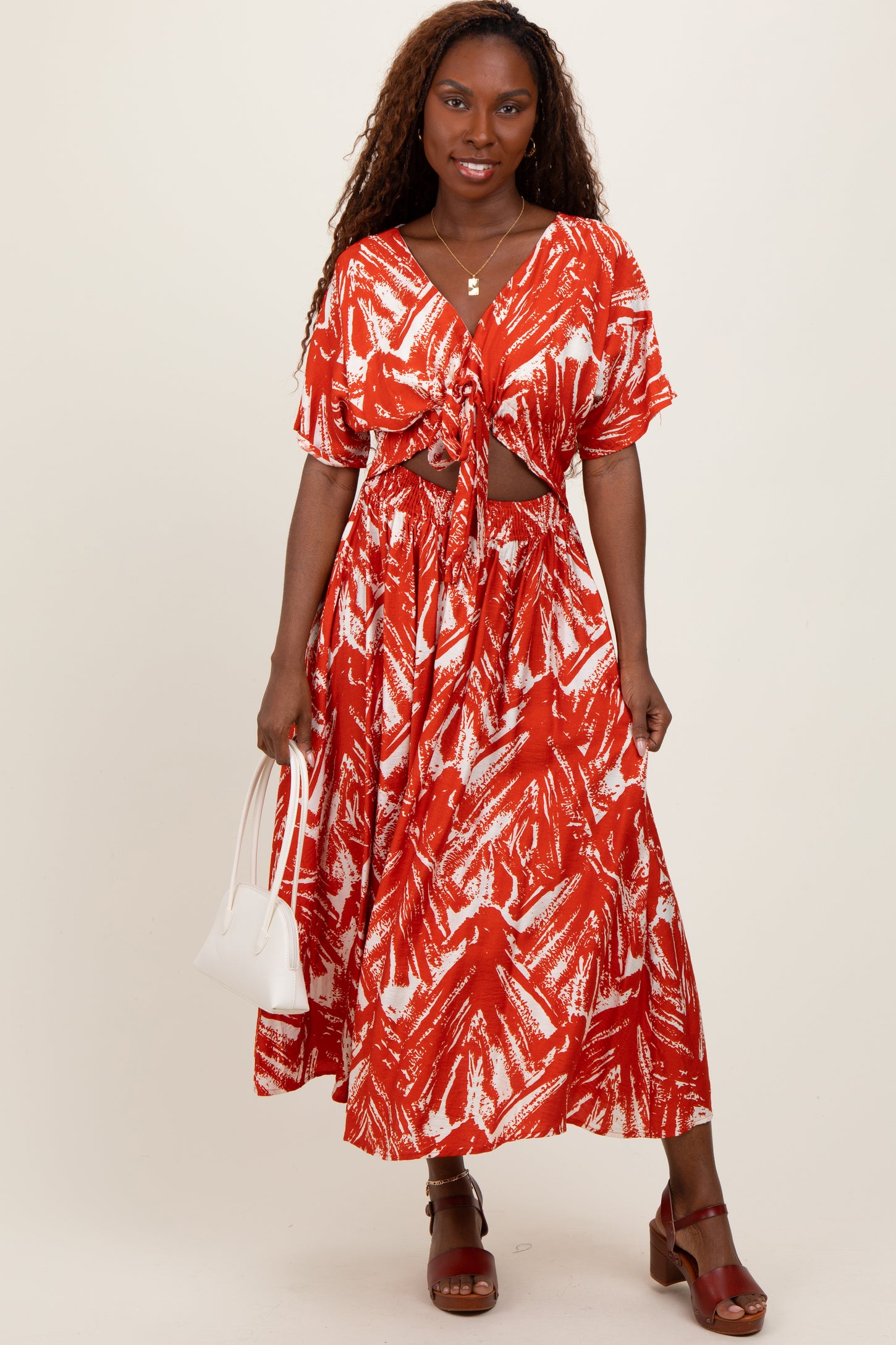 woman wearing a red and white patterned maxi dress with a knotted front and short sleeves