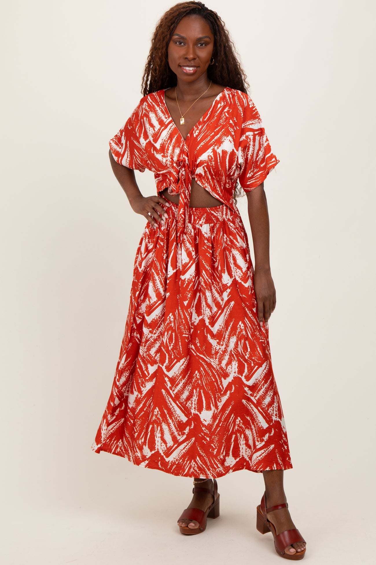 woman wearing a red and white printed two-piece set with a knotted top and a flowy maxi skirt