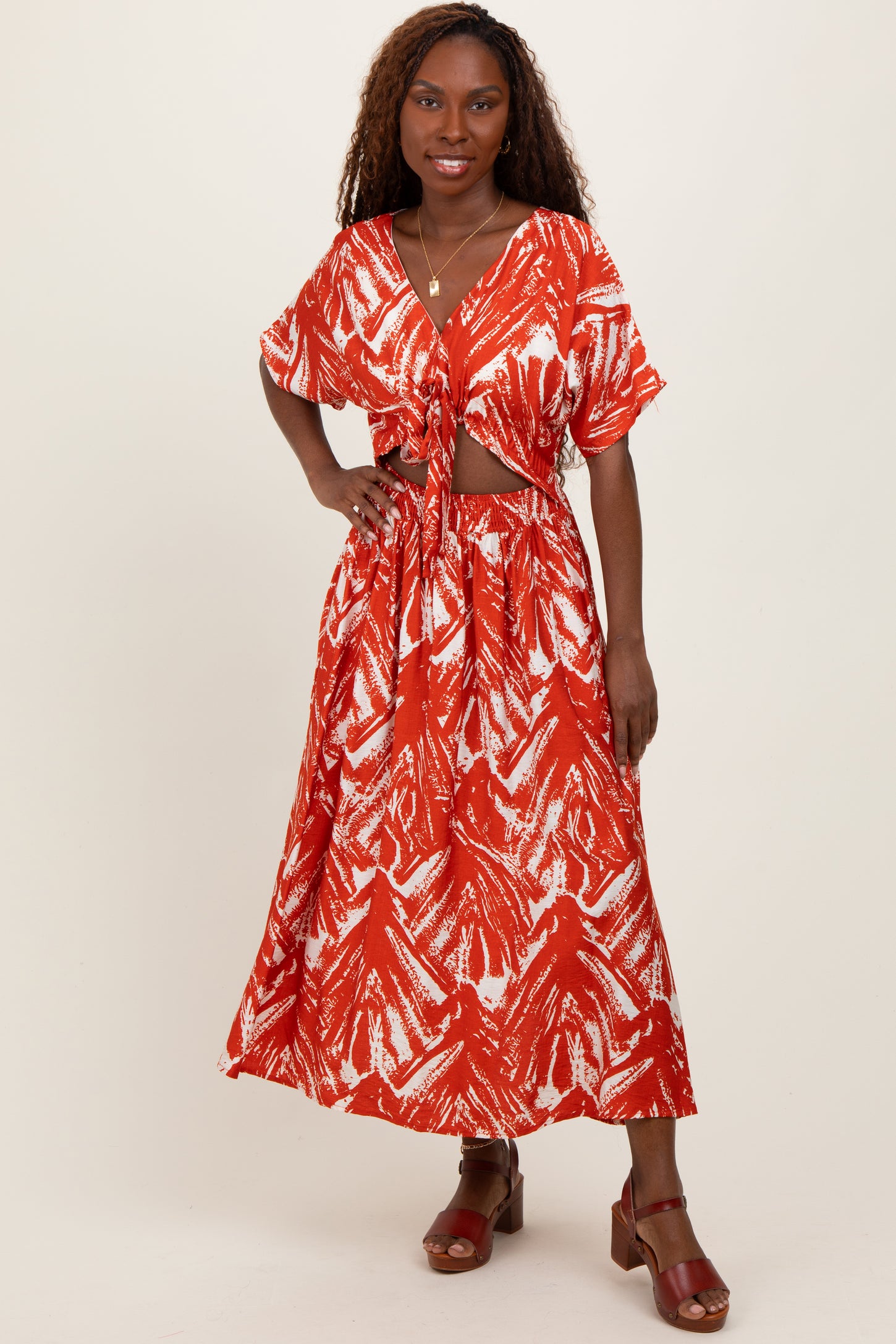 woman wearing a red and white printed two-piece set with a knotted top and a flowy maxi skirt