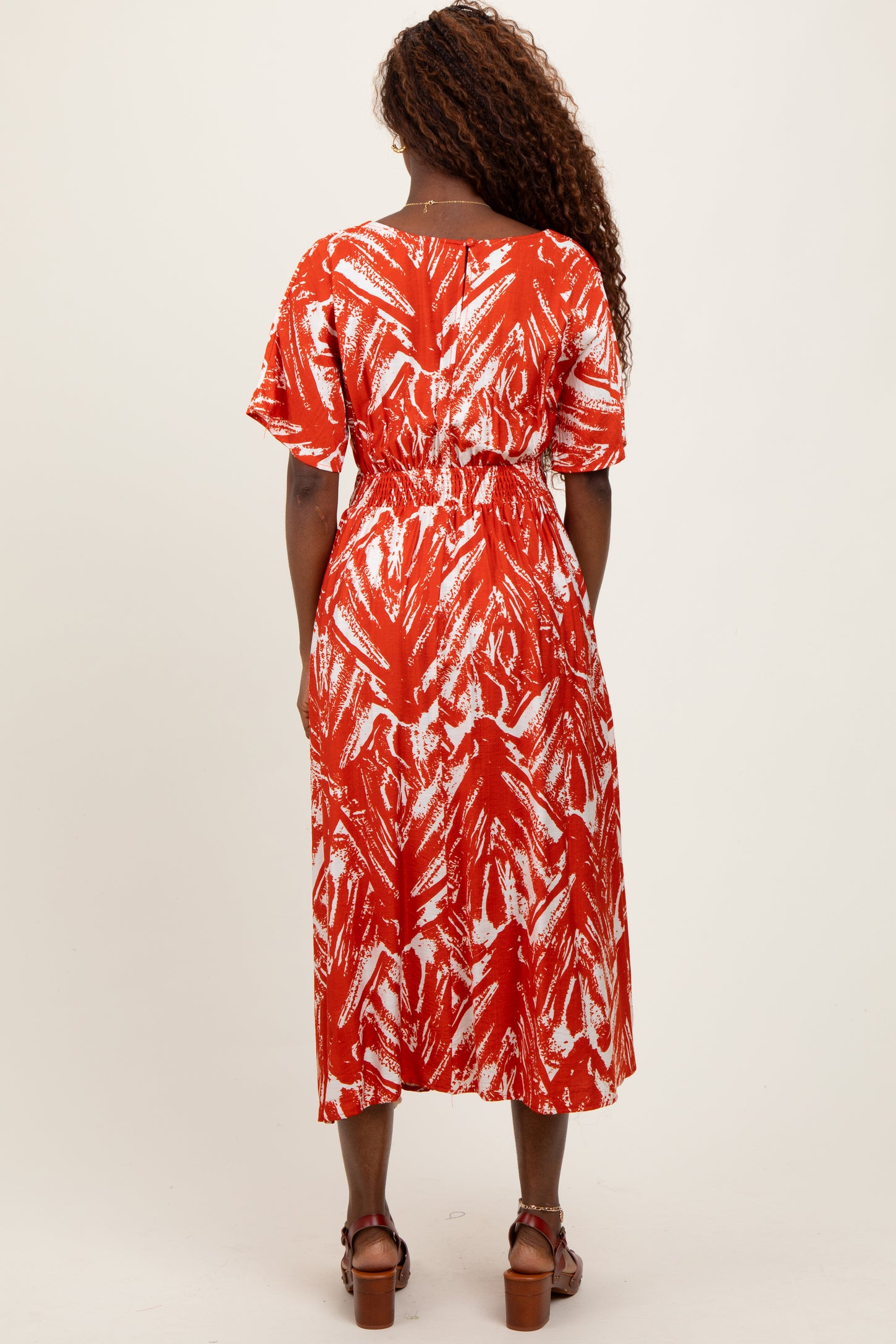 woman wearing a red and white patterned midi dress with short sleeves and an elastic waist, seen from the back