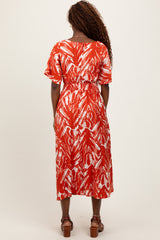 woman wearing a red and white patterned midi dress with short sleeves and an elastic waist, seen from the back