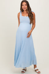 woman wearing a light blue maternity maxi dress with tie straps and a flowing skirt, showing her baby bump