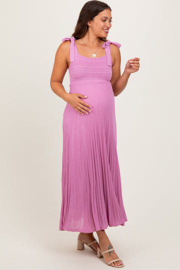 woman wearing a pink maxi maternity dress with tie straps and a visible baby bump