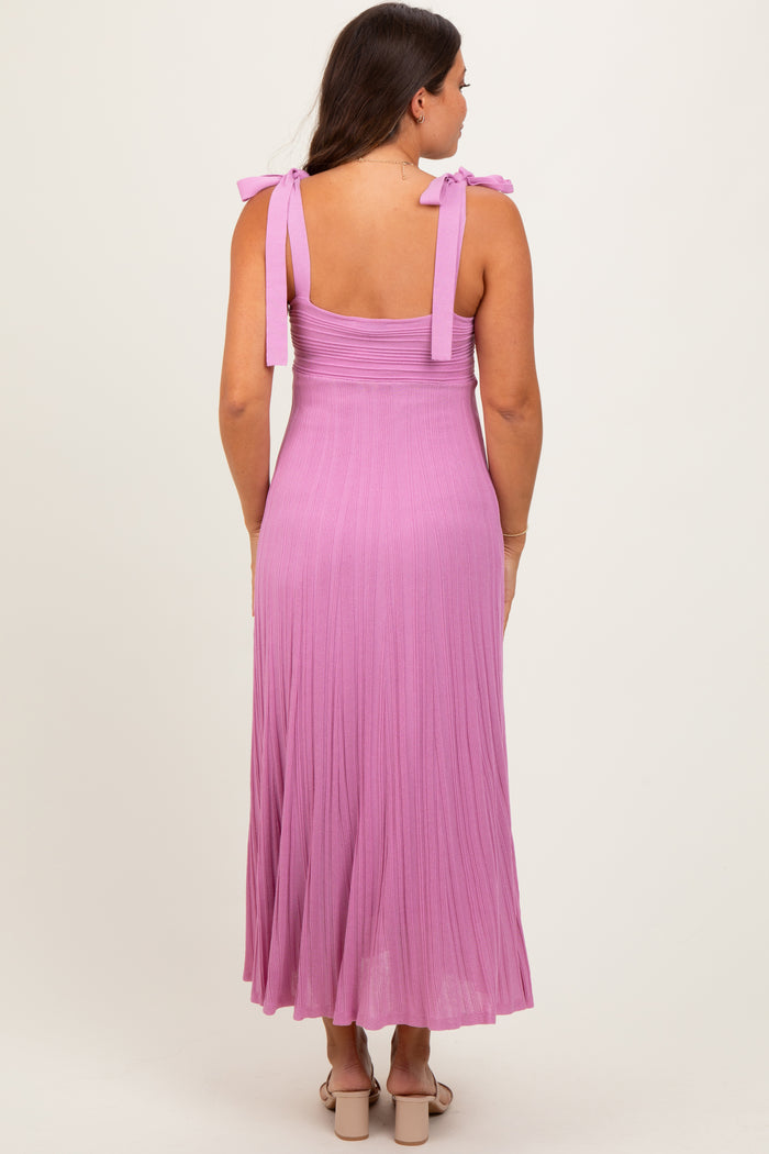woman wearing a light purple maternity dress with tie straps and a flowing skirt, showing her back