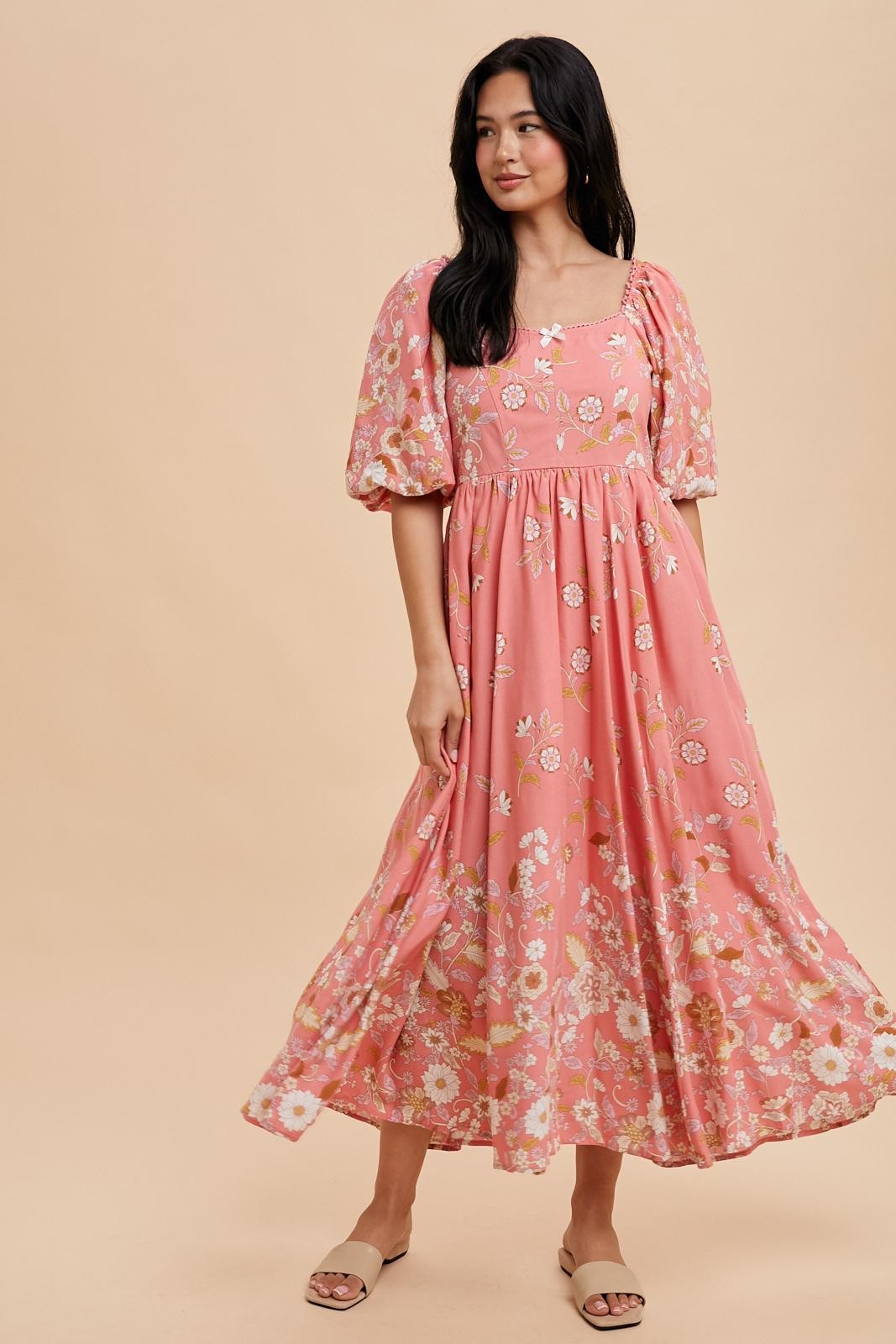 woman wearing a pink floral maxi dress with puff sleeves and a square neckline