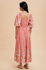 woman wearing a pink floral midi dress with puff sleeves and a smocked back, standing against a neutral background