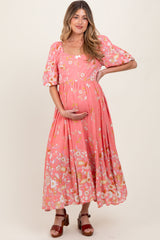 woman wearing a pink floral maternity maxi dress and holding her baby bump
