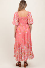 woman wearing a pink floral maternity dress with puff sleeves and a smocked back, shown from the back
