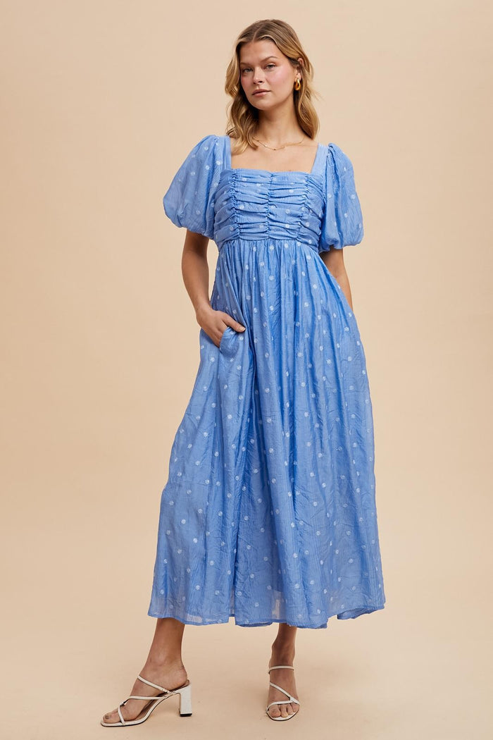 woman wearing a light blue maxi dress with puff sleeves and pockets, styled with strappy heels