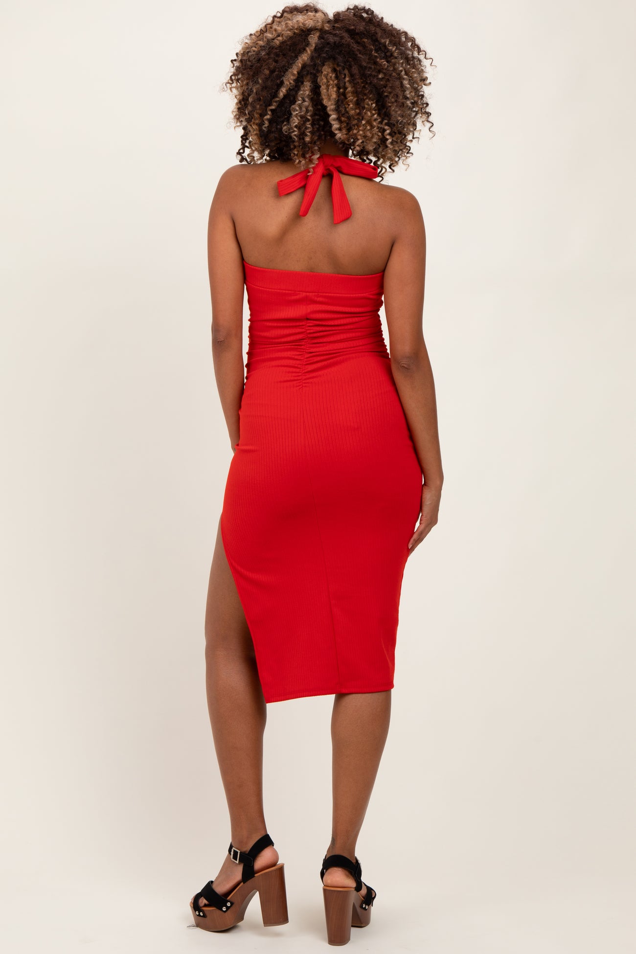 woman wearing a red maternity dress with back tie and side slit, showcasing a baby bump