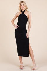 woman wearing a black halter neck midi dress with a side slit and ruching detail