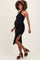 woman wearing a fitted black maternity dress with a halter neck and side slit, showcasing her baby bump