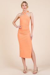 woman wearing an orange ribbed halter neck midi dress with a side slit and gathered detailing