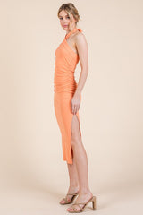 woman wearing an orange ribbed one-shoulder midi dress with side slits and ruched detailing