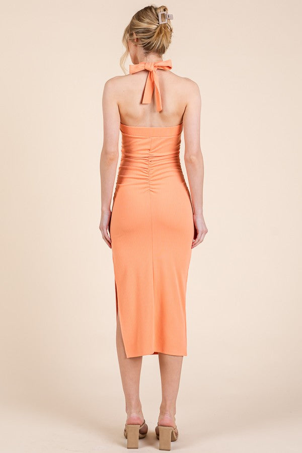 woman wearing a peach ribbed midi dress with a halter neck and back ruching details