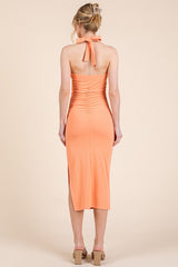 woman wearing a peach ribbed midi dress with a halter neck and back ruching details
