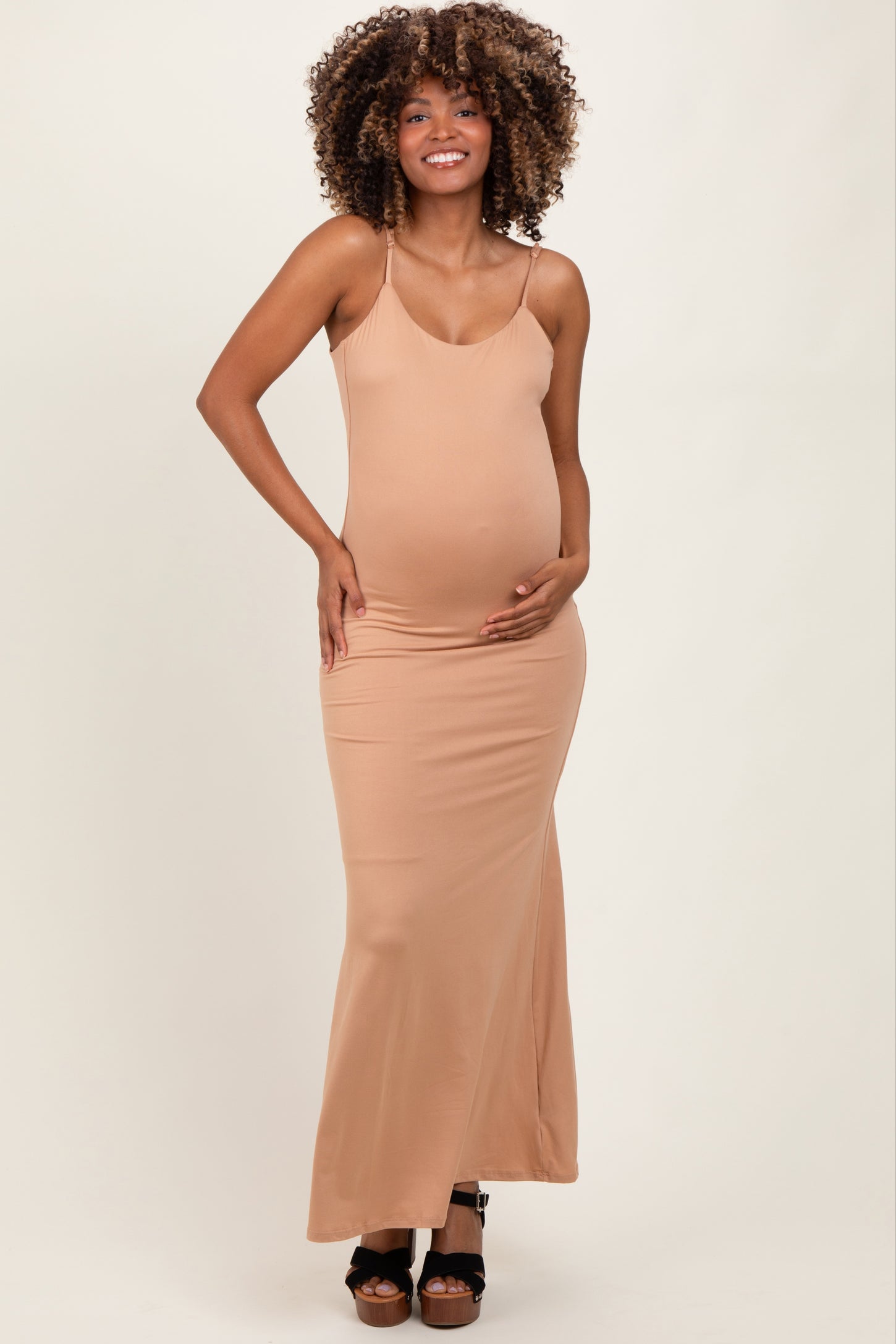 woman wearing a nude maternity maxi dress and holding her baby bump