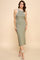 woman wearing a ribbed olive green midi dress with white trim and side slits, standing in a neutral background