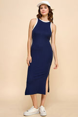 woman wearing a navy ribbed maxi dress with white trim and side slit, styled with a white cap and white sneakers