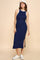 woman wearing a navy ribbed maxi dress with white trim and side slit, styled with a white cap and white sneakers