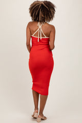 woman wearing a red halter neck maternity dress with a fitted silhouette and mid-length hem, showing her back