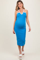 woman wearing a blue halter neck maternity dress with white trim and a visible baby bump