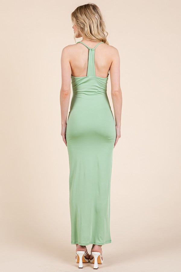 woman wearing a green backless maxi dress with a halter neck and fitted silhouette