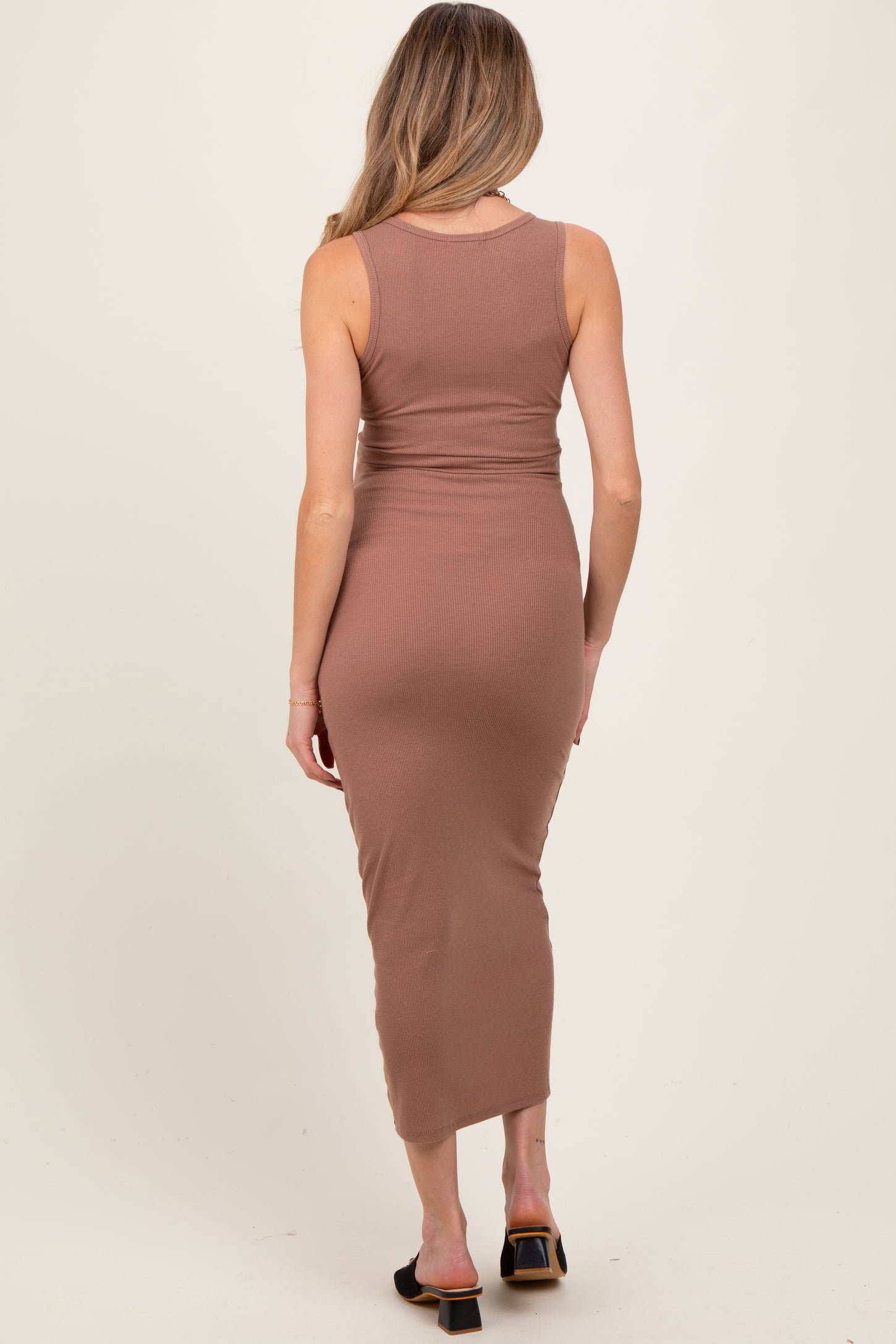 woman wearing a brown ribbed maternity dress with a fitted silhouette and midi length