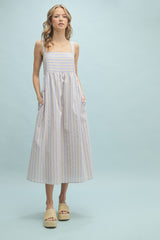 woman wearing a striped midi dress with a square neck, spaghetti straps, and pockets