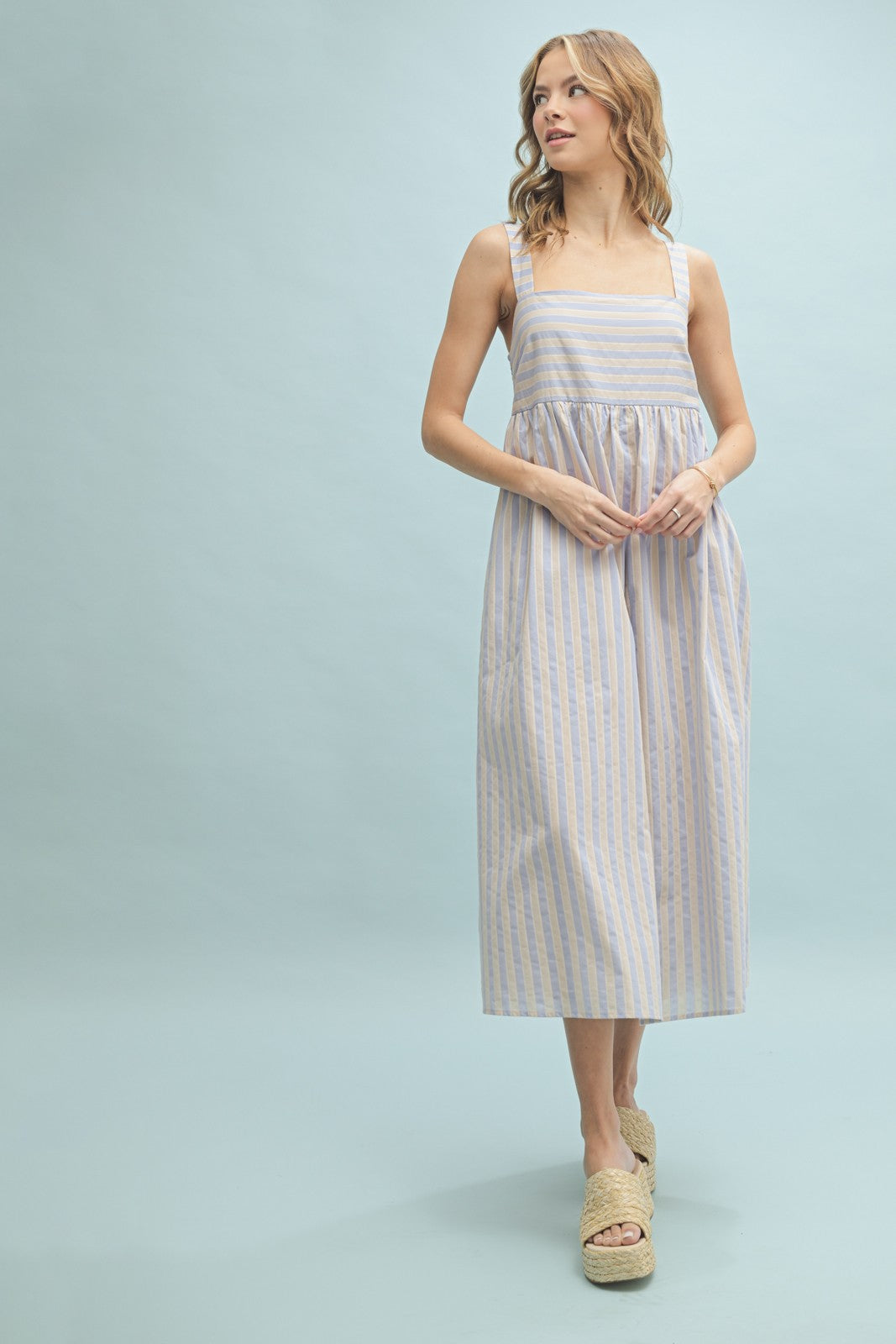 woman wearing a light blue and white striped maxi dress with square neckline and wide straps