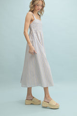 woman wearing a light purple and white striped midi dress with a fitted bodice and flowy skirt, styled with tan platform sandals