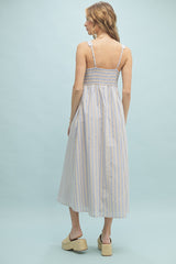 woman wearing a light blue and white striped midi dress with smocked back and thin shoulder straps