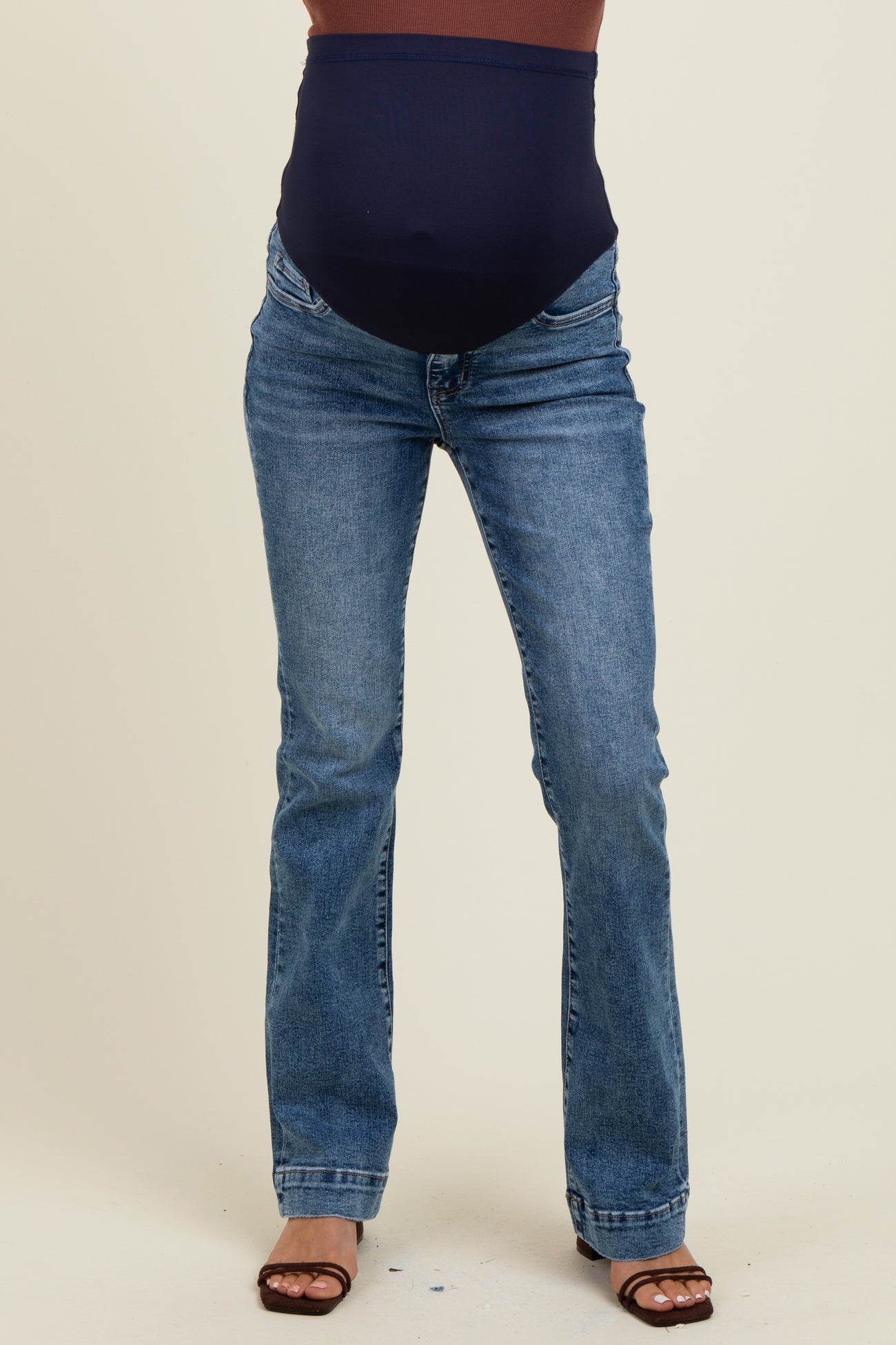 woman wearing maternity blue bootcut jeans with a black over-the-bump waistband and brown sandals