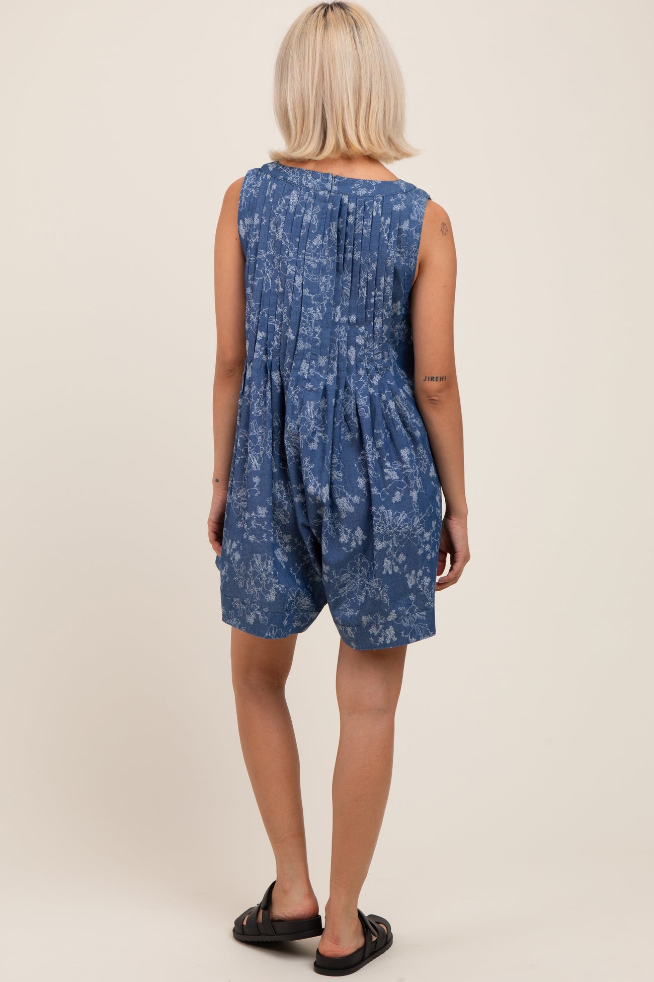 woman wearing a blue floral maternity romper with pleated back detail and relaxed fit