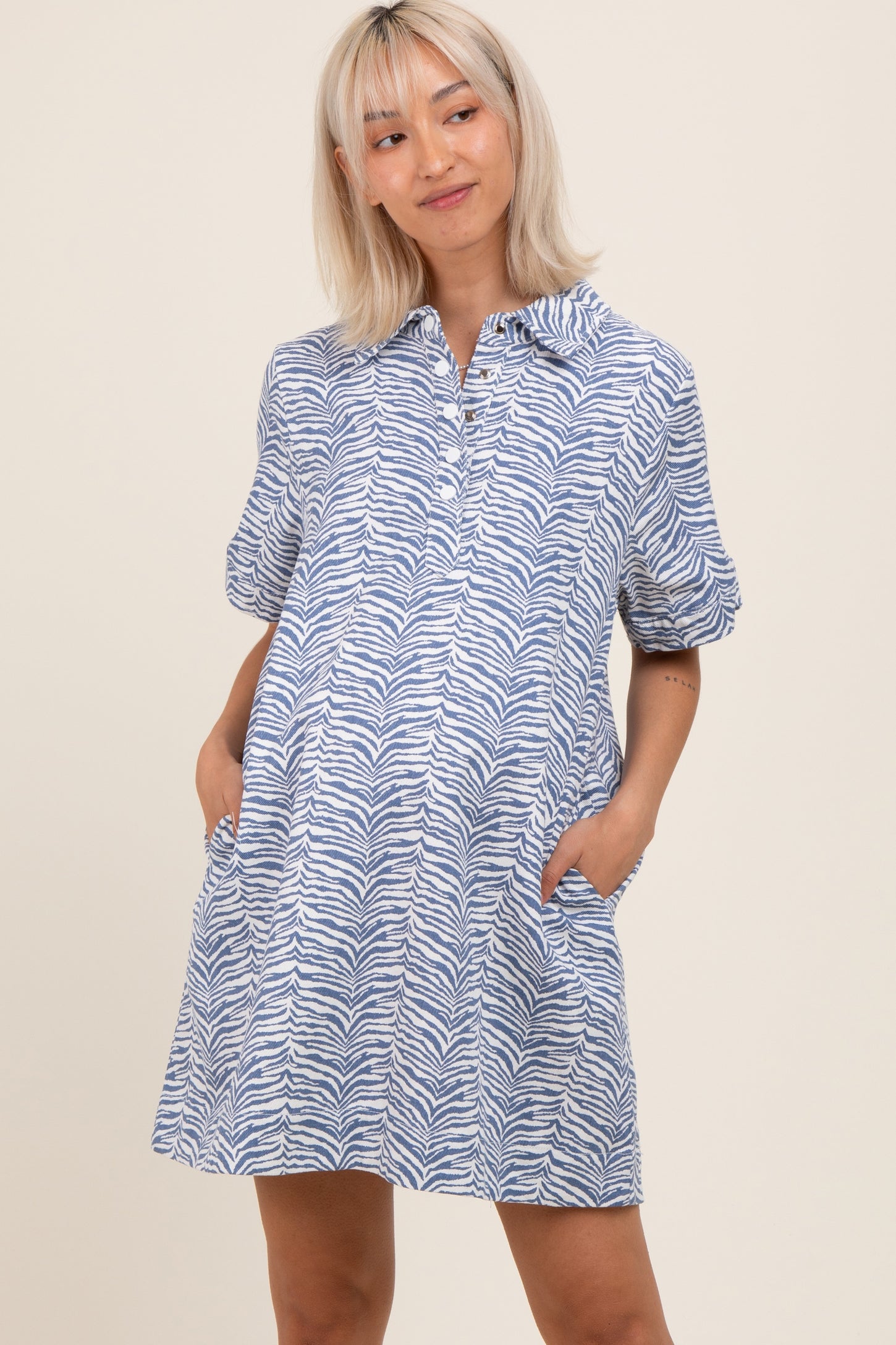 woman wearing a blue and white zebra print maternity dress with a collared neckline and pockets
