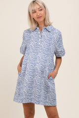 woman wearing a blue and white zebra print maternity dress with a collared neckline and pockets