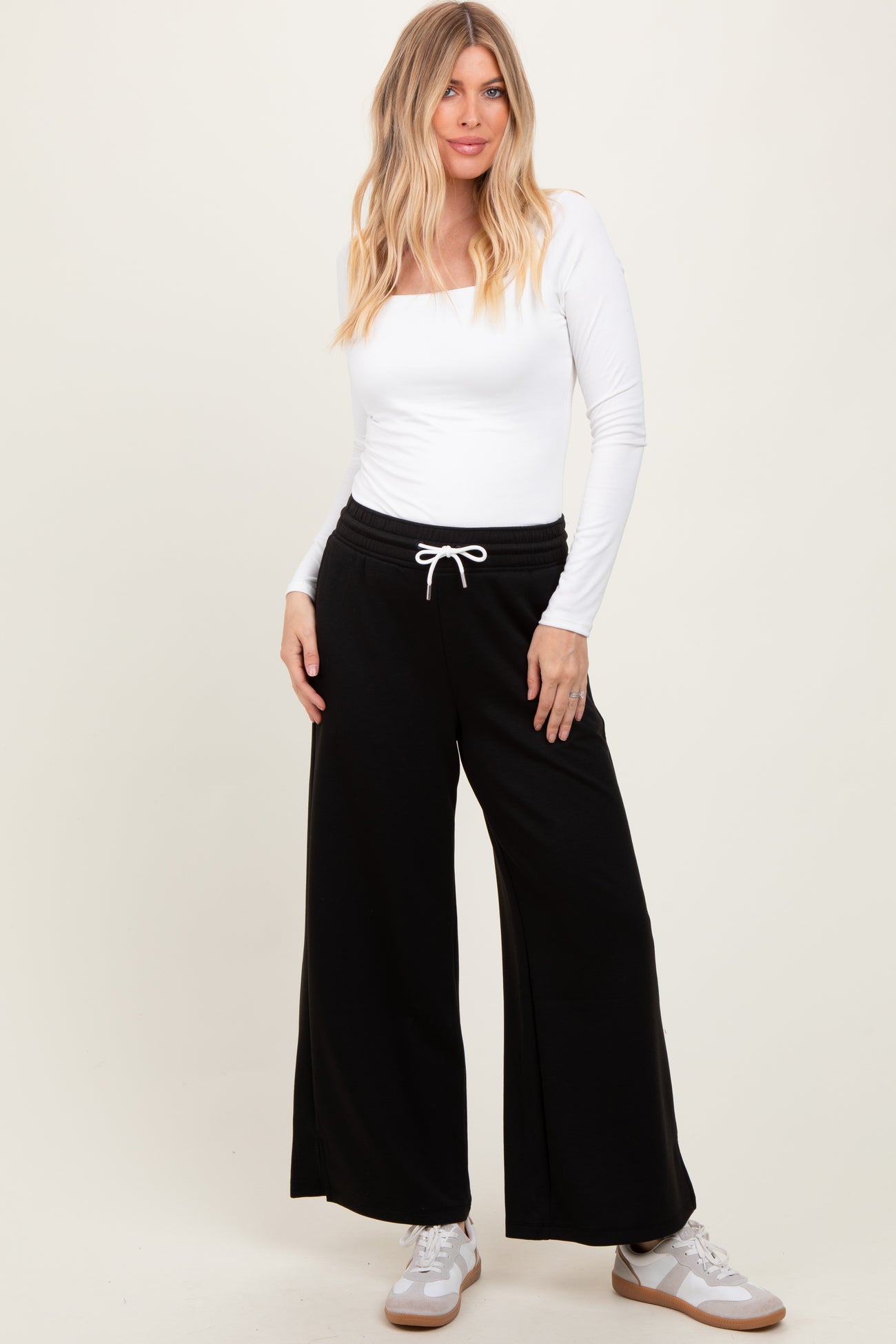 woman wearing a white long sleeve fitted top and black wide-leg sweatpants with a drawstring waist