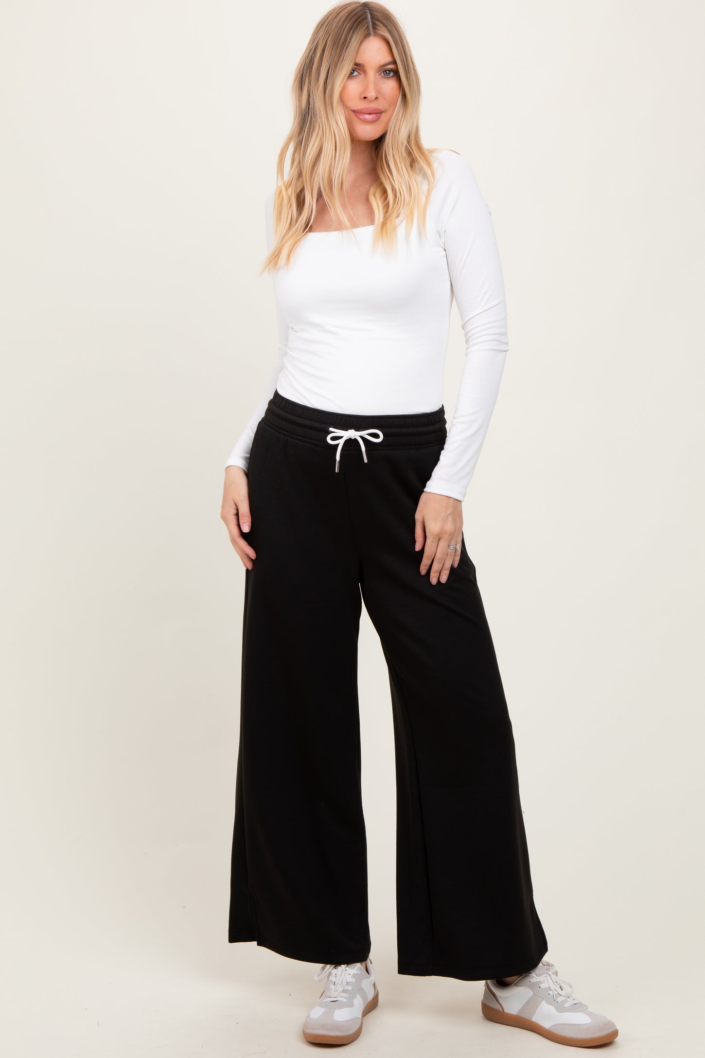 woman wearing a white long sleeve fitted top and black wide-leg sweatpants with a drawstring waist