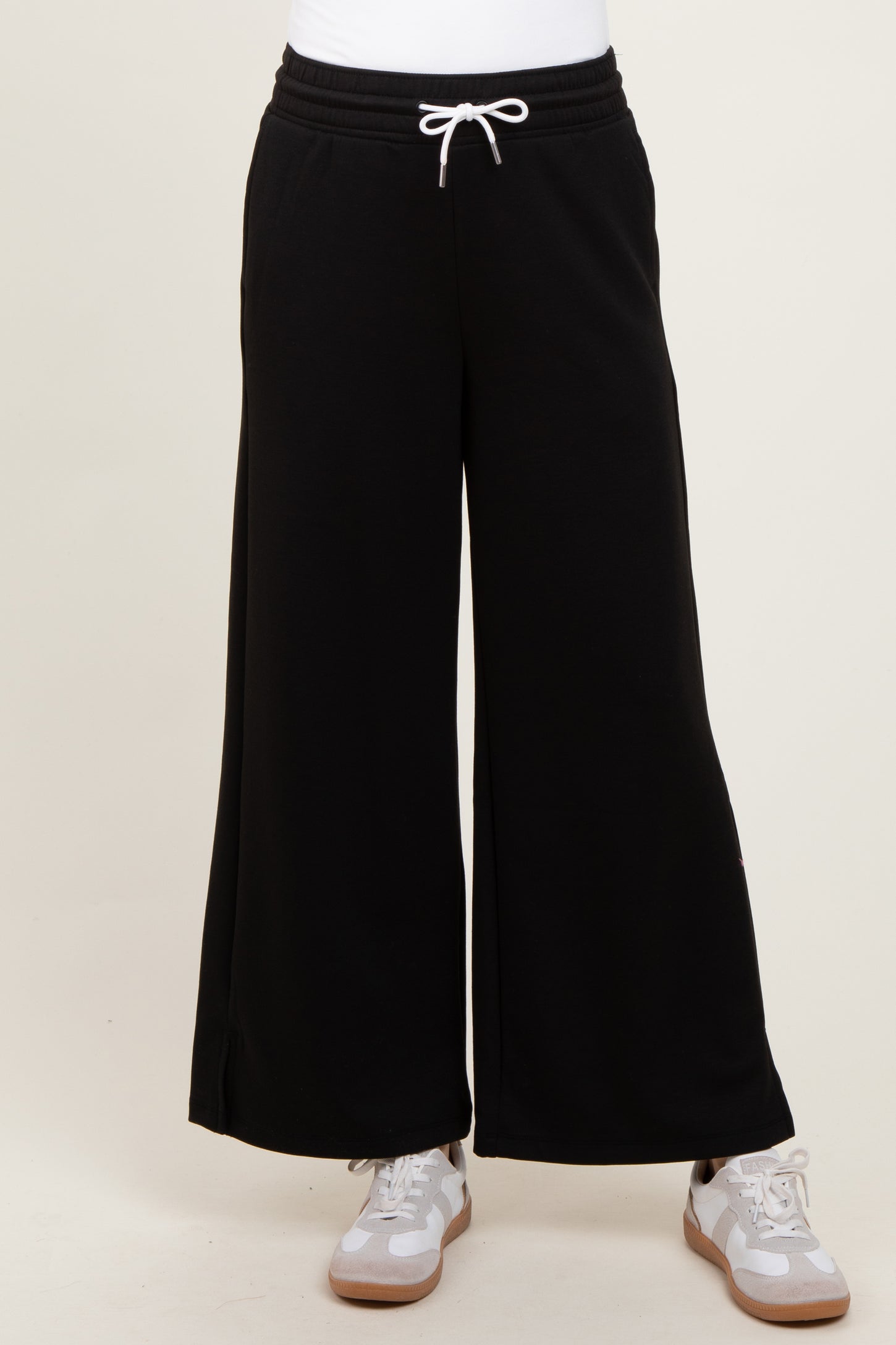 black wide-leg sweatpants with drawstring waistband styled with a white top and gray sneakers