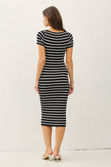 woman wearing a black and white striped fitted midi dress while standing with her back to the camera