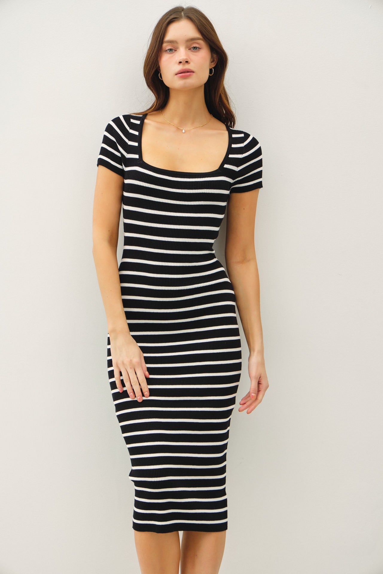 woman wearing a black and white striped fitted midi dress with short sleeves and a square neckline