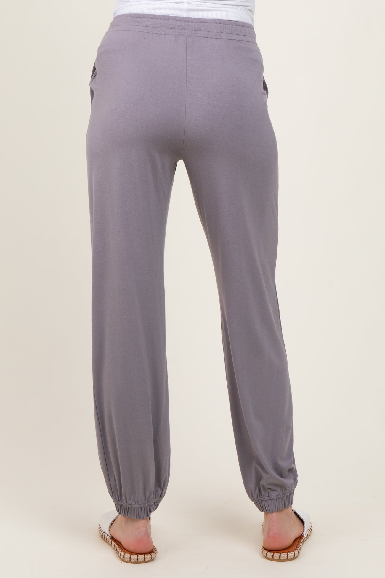 woman wearing light gray maternity jogger pants with elastic cuffs and side pockets, showing back view
