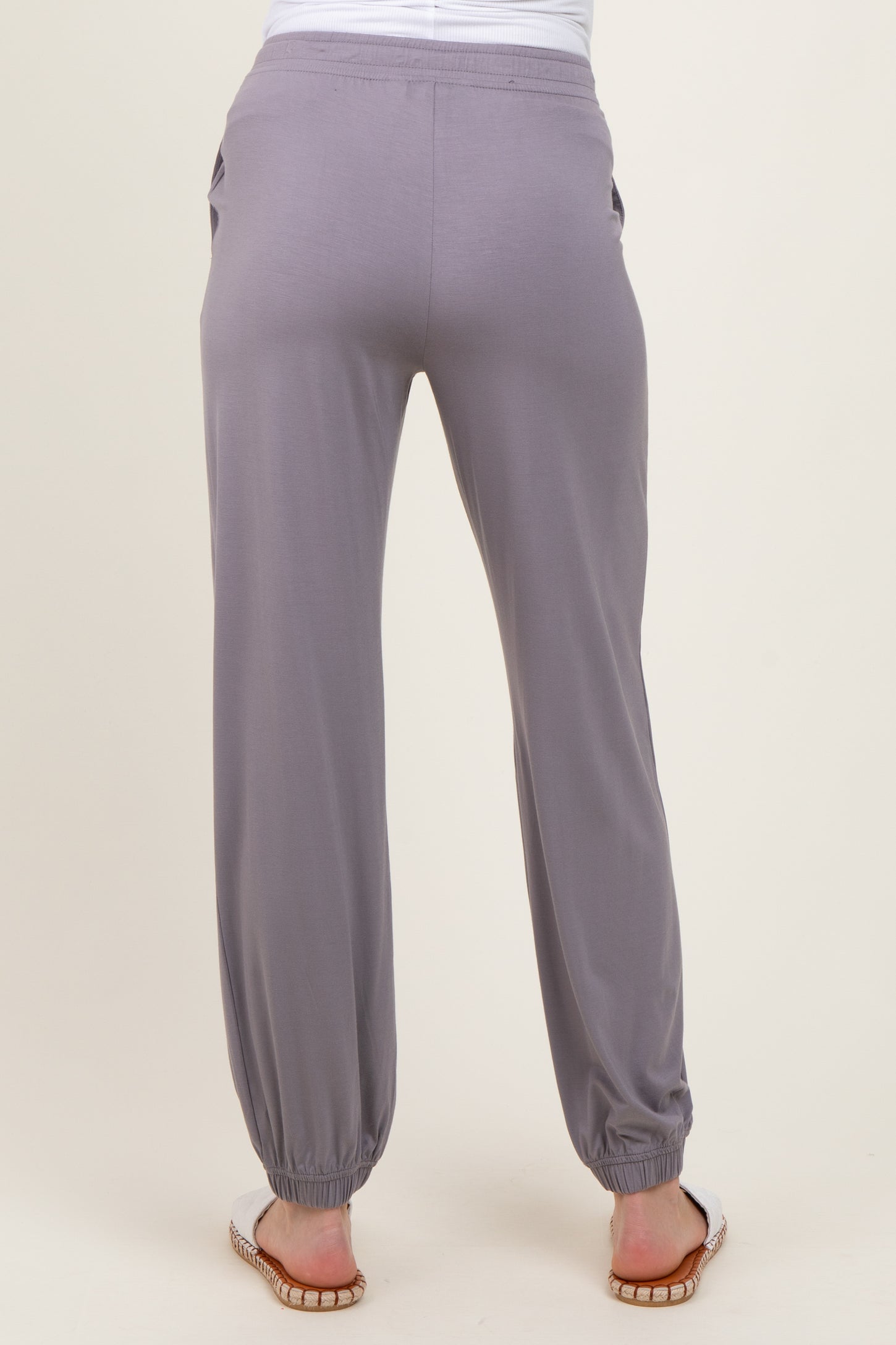 woman wearing light gray maternity jogger pants with elastic cuffs and side pockets, showing back view