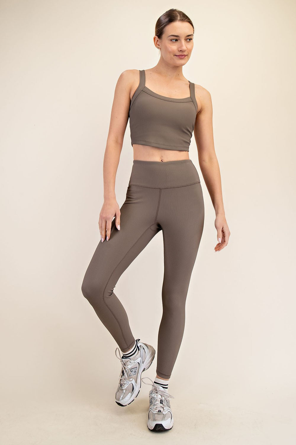 woman wearing a brown ribbed crop top and matching high-waisted leggings, paired with sporty sneakers