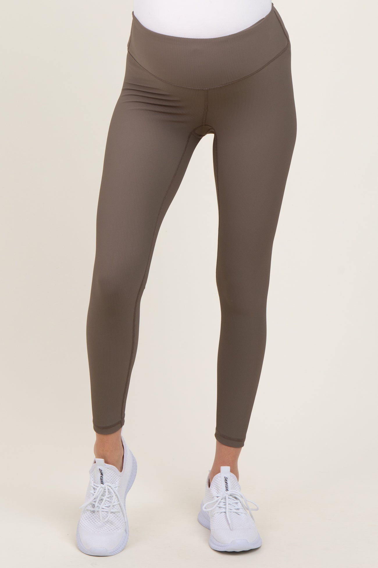 woman wearing brown maternity leggings with a high waist and white athletic shoes