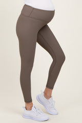woman wearing brown maternity leggings that fit over her baby bump, paired with white athletic shoes