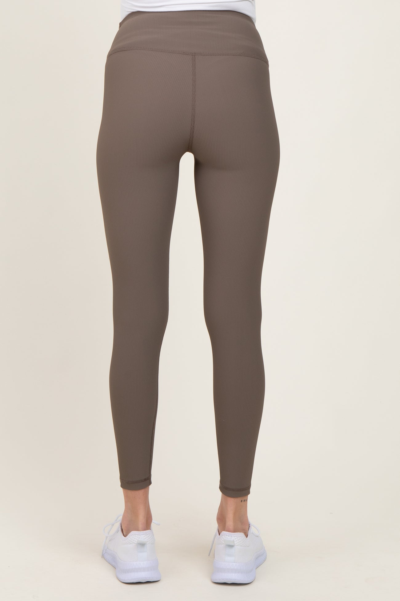 woman wearing brown maternity leggings, viewed from the back, with a smooth, stretchy fabric and fitted style