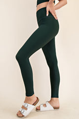 woman wearing dark green high-waisted leggings and white slide sandals