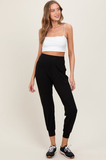 woman wearing a cropped white tank top and black jogger pants with elastic waistband and tapered cuffs