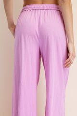 woman wearing light pink loose-fitting pants, showing the back view and elastic waistband